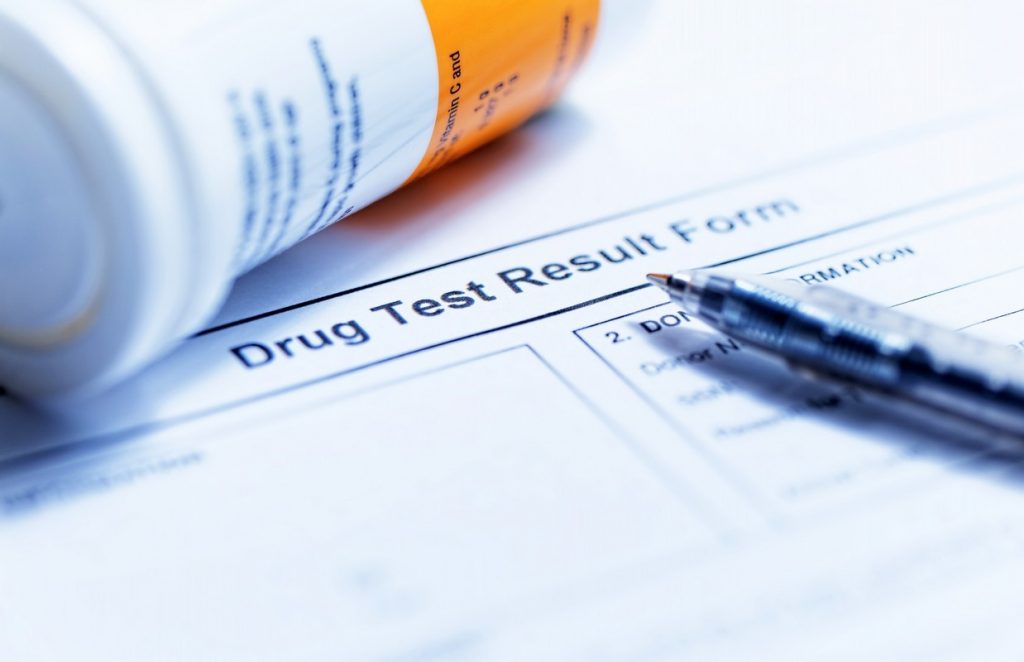 Close up of drug test form, pen, and bottle